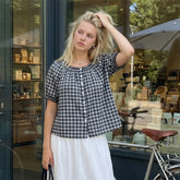 Woman standing in front of a store window with a bicycle nearby