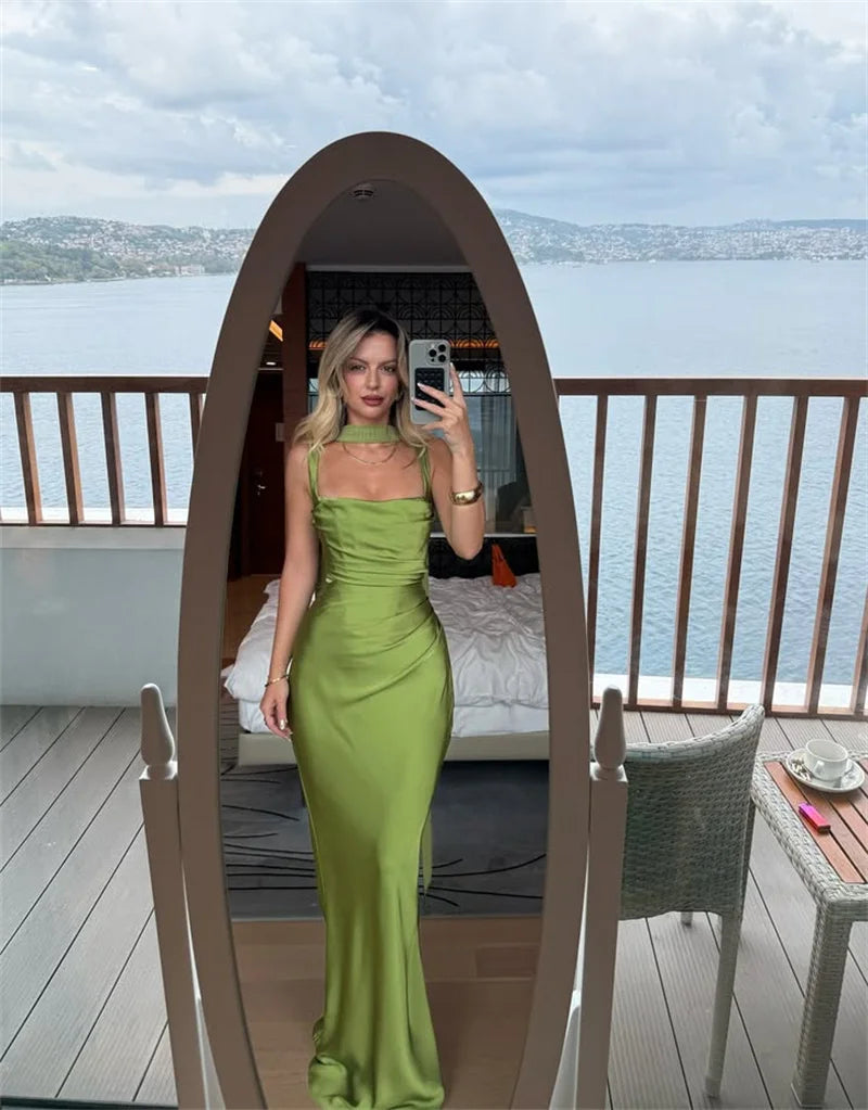 Woman in a green dress taking a mirror selfie on a balcony with a scenic view.