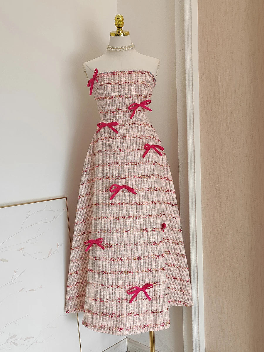 Dress with pink bows on a mannequin against a neutral wall.