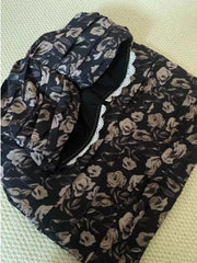 Floral patterned scarf with black background on a light green surface