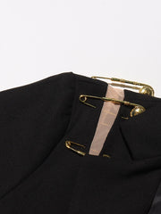 Black blazer with gold safety pins on a white background