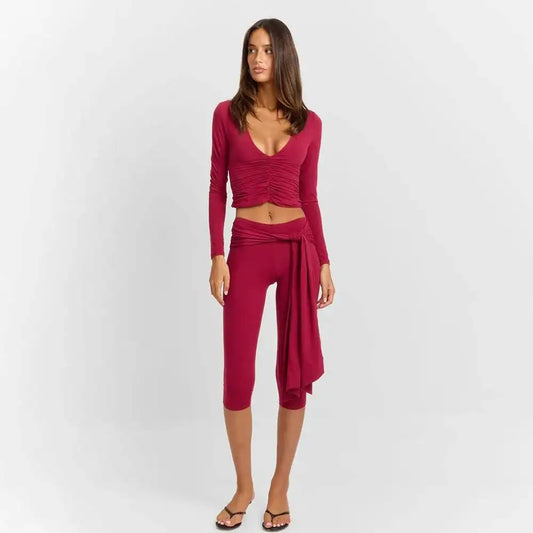 Model wearing a ruched v-neck long sleeve crop top and bandage capri pants set.