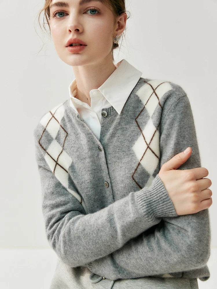 Woman wearing a gray argyle sweater over a white shirt on a light background