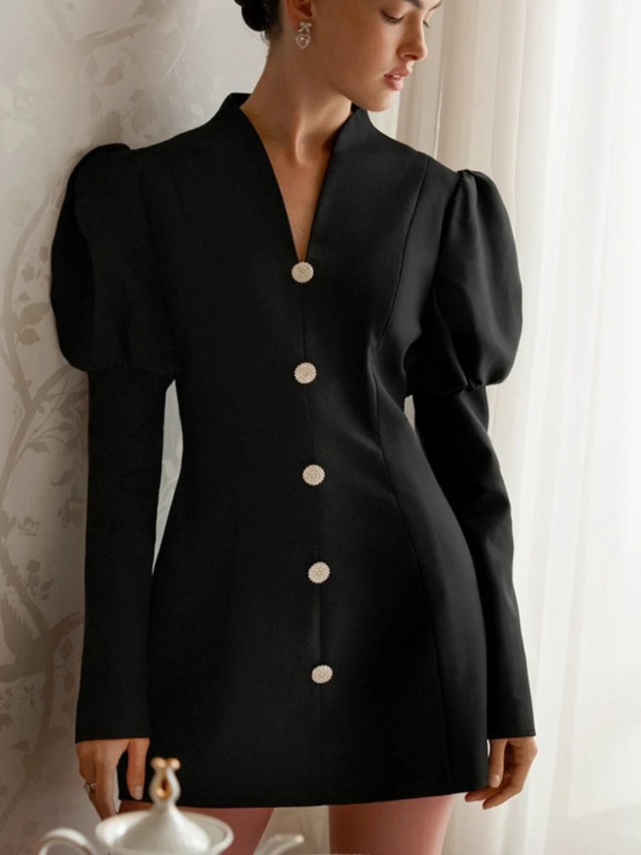 Black dress with puff sleeves and buttons worn by a person against a neutral background
