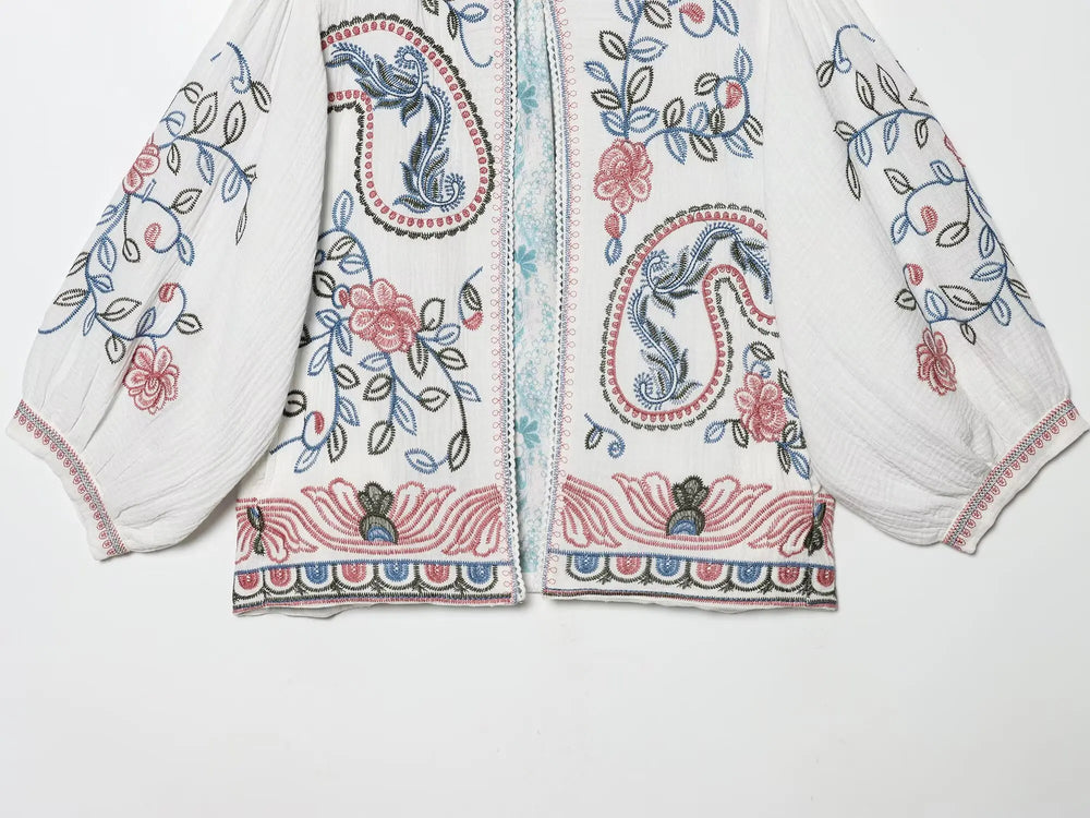 Detailed view of the bottom hem and embroidery on the white blouse.