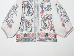 Detailed view of the bottom hem and embroidery on the white blouse.