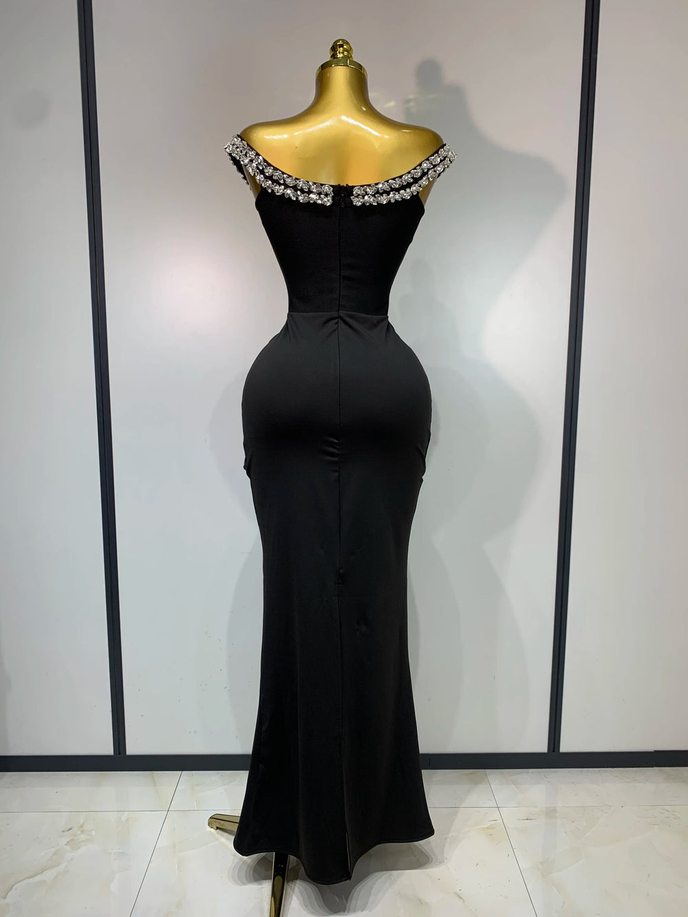 Back view of an off-the-shoulder draped bandage dress with diamond embellishments