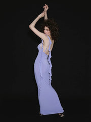 Woman in a long, light purple dress with ruffled details against a black background
