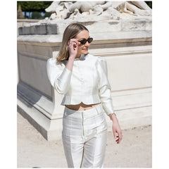 Woman in a white outfit standing in front of a classical building.