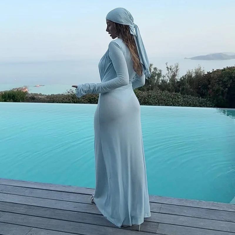 Woman in a white dress standing by an infinity pool with a scenic view.