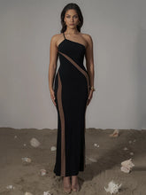 Woman wearing a black halter neck dress with sheer panels on a neutral background