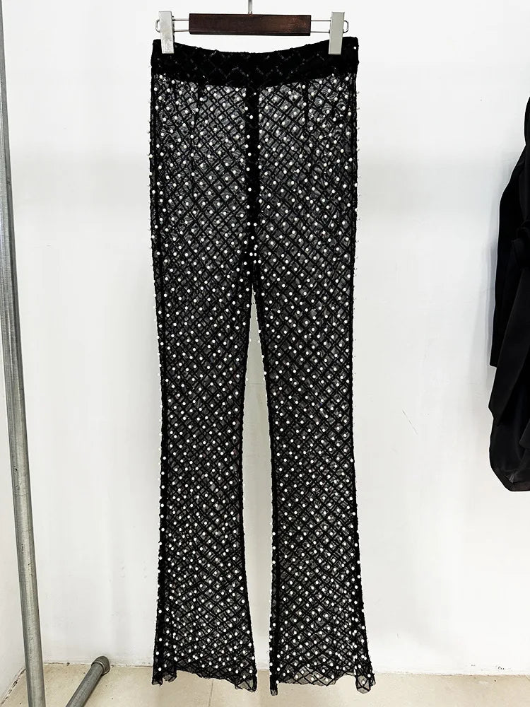 Black pants with white pattern hanging on a rack against a white background