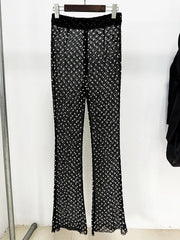 Black pants with white pattern hanging on a rack against a white background