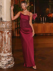 Woman in a burgundy evening gown standing next to a decorative column in an elegant indoor setting.