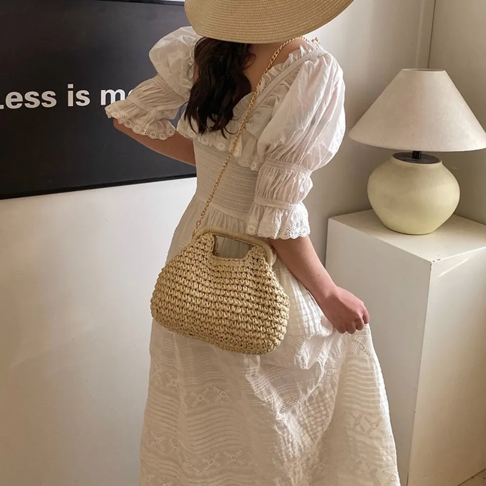 Woman in a white dress holding a straw bag indoors