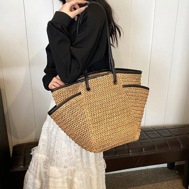 Person holding a woven handbag against a neutral background