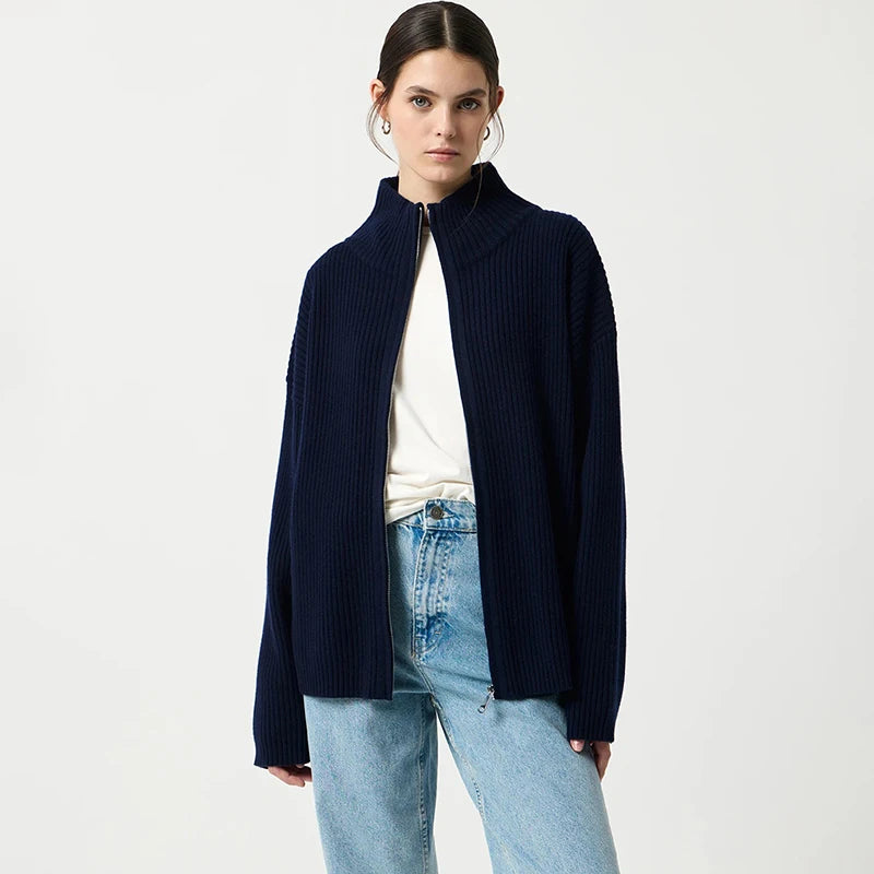 Woman wearing a navy blue cardigan over a white shirt and light blue jeans on a white background