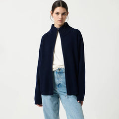 Woman wearing a navy blue cardigan over a white shirt and light blue jeans on a white background