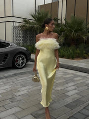 Woman in a yellow dress with feathered top walking outdoors.