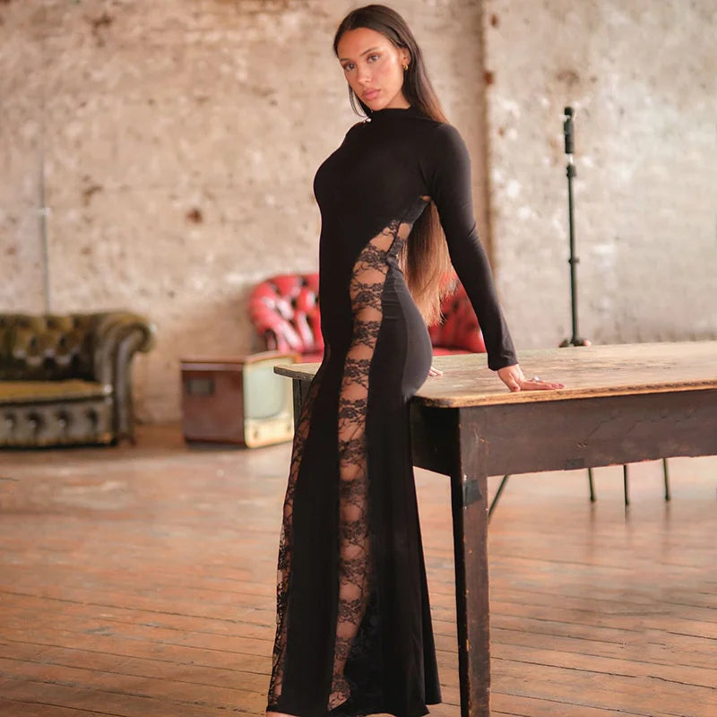 Woman in a black dress with lace detailing standing on a wooden table in an industrial-style room.