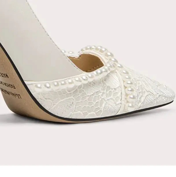 White high-heeled shoe with lace detailing on a light gray background