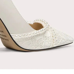 White high-heeled shoe with lace detailing on a light gray background