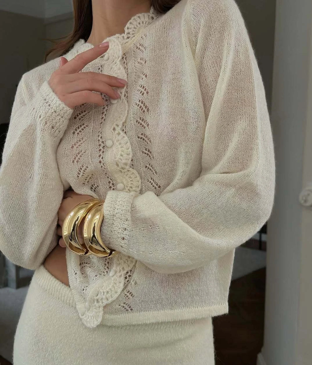 Close-up of a person wearing a beige knit sweater with lace details.