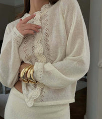 Close-up of a person wearing a beige knit sweater with lace details.