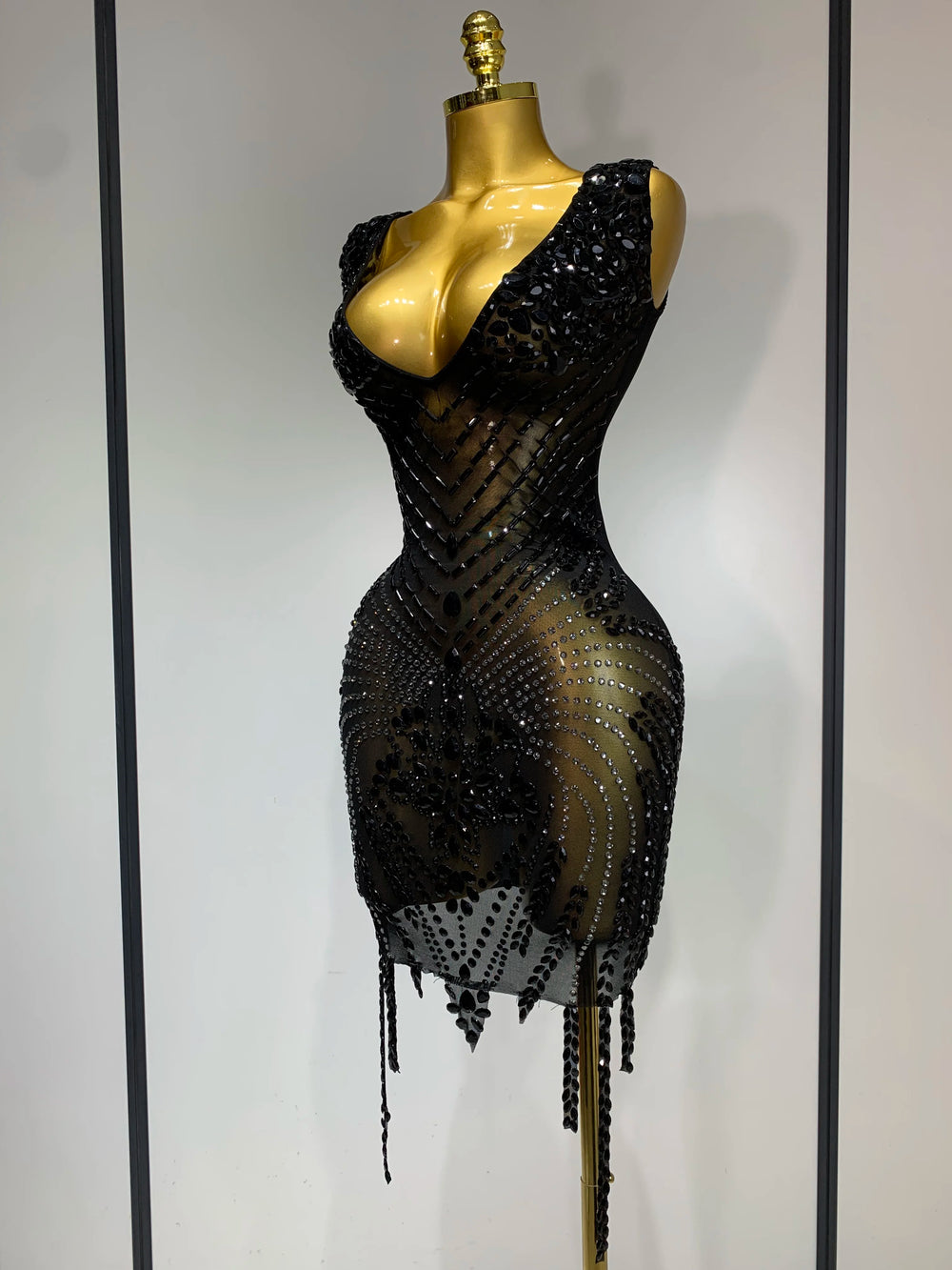 Black beaded dress on a mannequin against a plain background