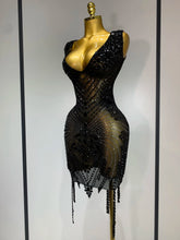Black beaded dress on a mannequin against a plain background
