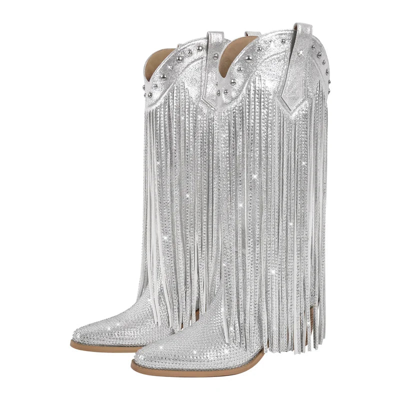 Silver cowboy boots with fringes and rhinestone embellishments on a white background