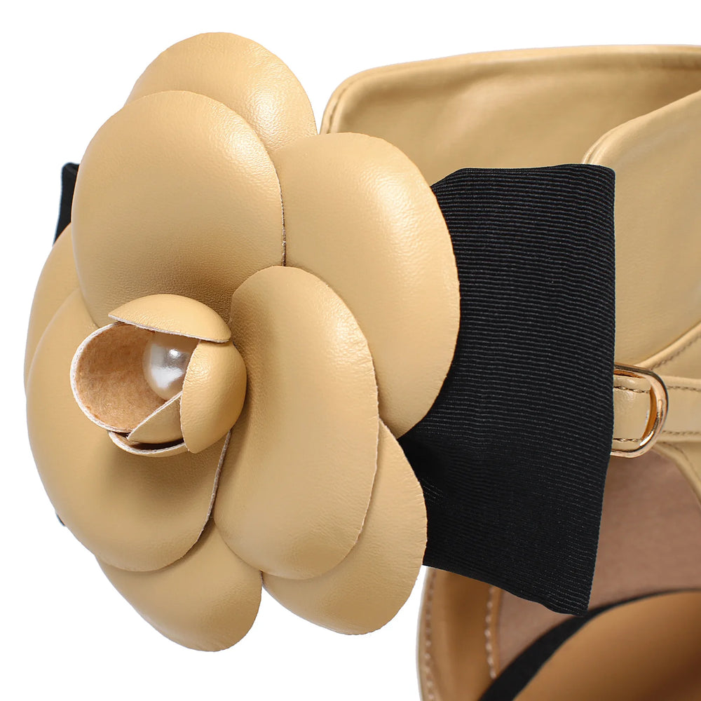 Close-up of a beige leather flower accessory on a black strap.