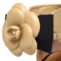 Close-up of a beige leather flower accessory on a black strap.