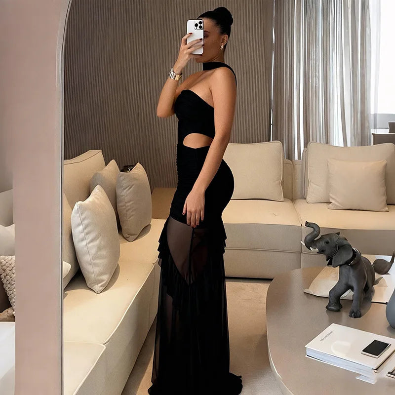Woman in a black dress taking a mirror selfie in a stylish living room.