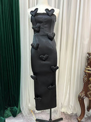 Black dress with heart-shaped cutouts on a mannequin against a white curtain background