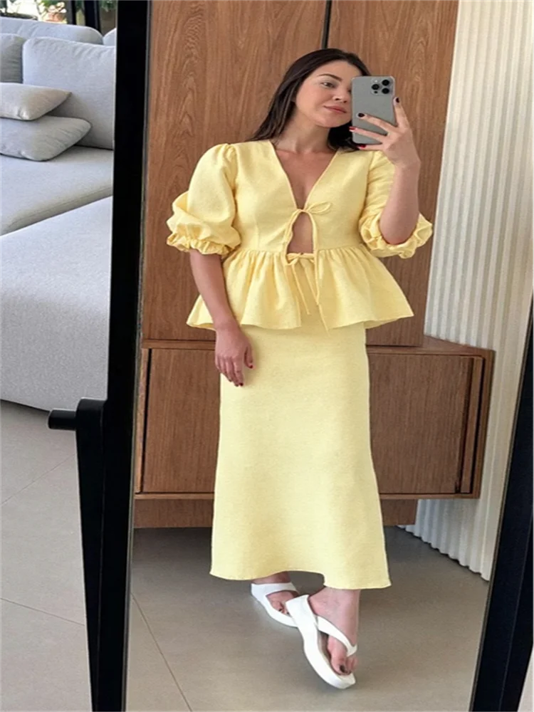 Woman taking a mirror selfie wearing a yellow dress in a room with wooden paneling.