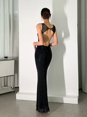 Woman wearing a black evening gown with open back in a minimal indoor setting