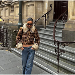Person wearing a leopard print coat with fur trim on a city street.