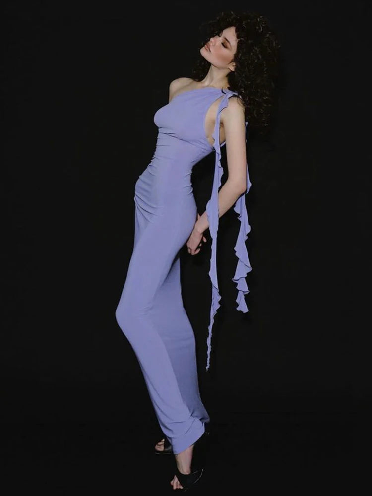 Woman wearing a lavender one-shoulder jumpsuit with ruffled details on a black background