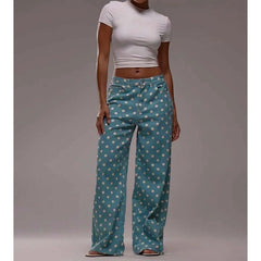 Person wearing teal pants with white polka dots and a white top on a gray background