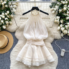 White dress on a hanger with floral decorations and a hat on a textured surface