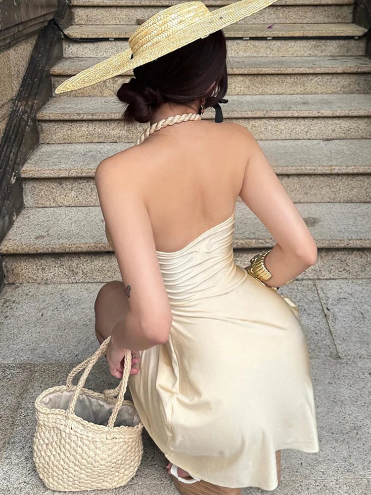 Woman in a white dress and straw hat sitting on stone steps.