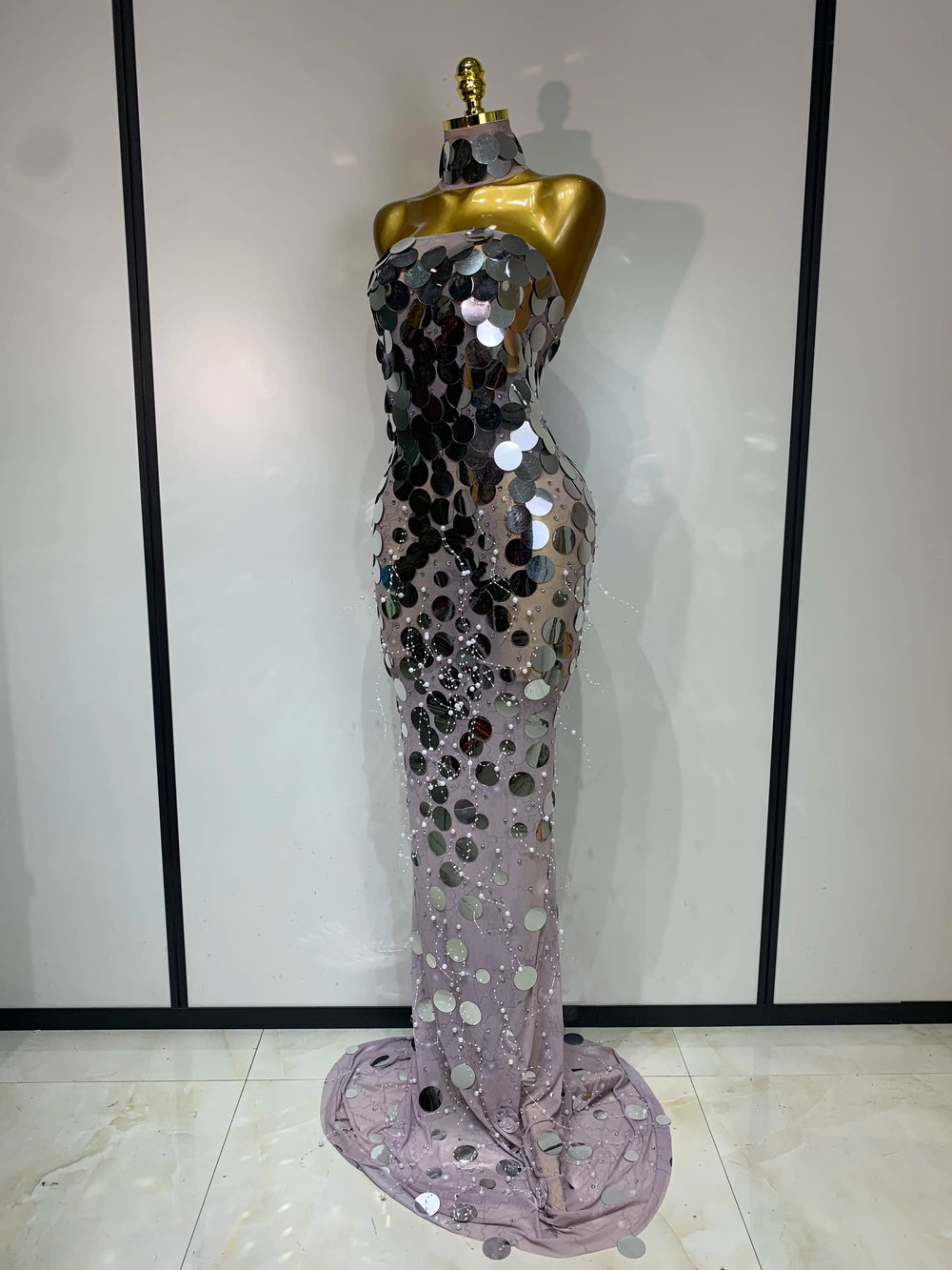 Silver sequin evening gown on a mannequin against a white wall.
