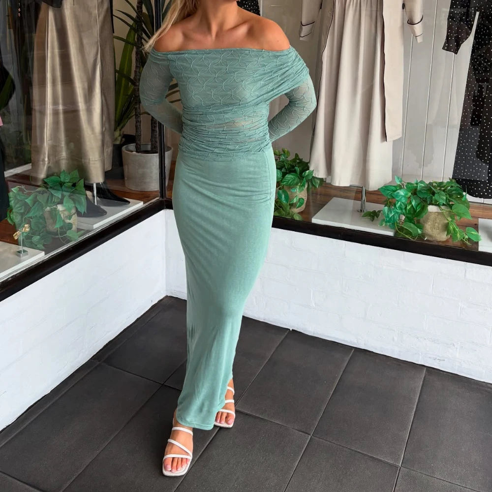 Person wearing a green off-shoulder dress in a room with plants and mirrors.