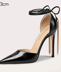 Black high-heeled shoe with a gold chain on a light gray background