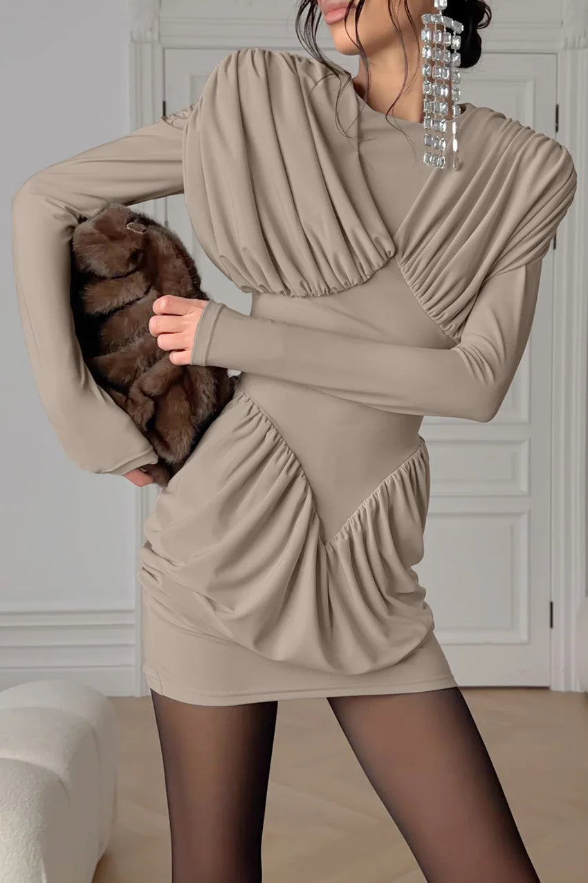 Woman wearing a beige dress holding a brown fur coat indoors.
