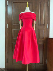 Red off-shoulder dress on a mannequin against a wooden door background