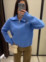 Person wearing a blue zip-up sweater taking a mirror selfie.