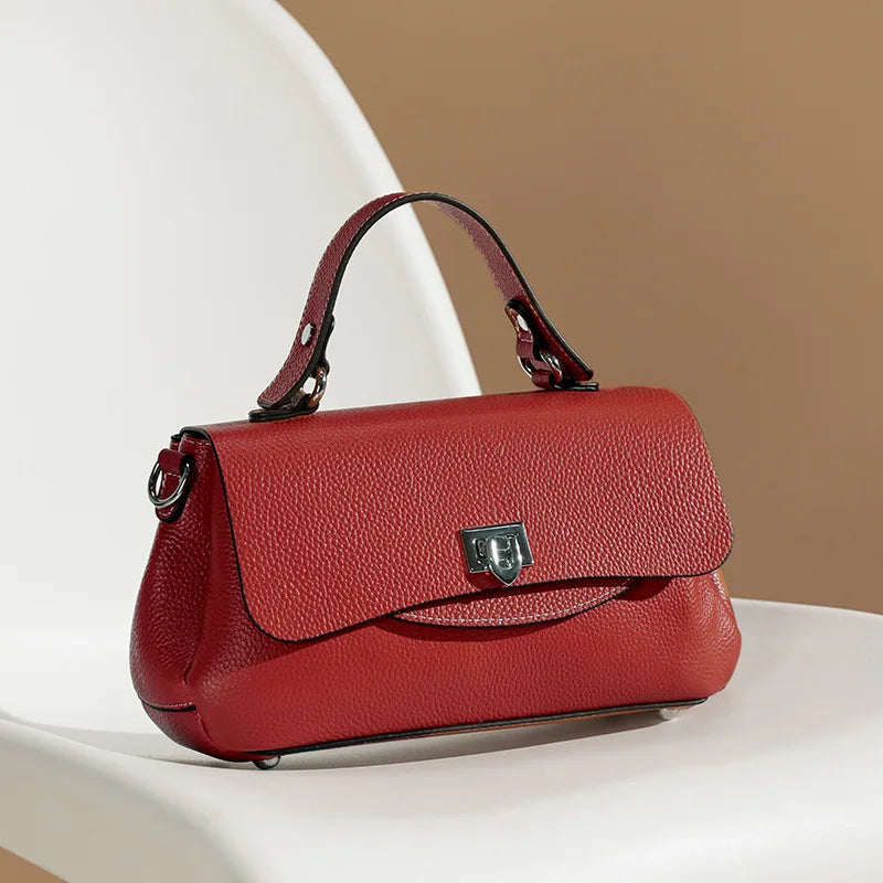 Red handbag on a white surface with a beige background