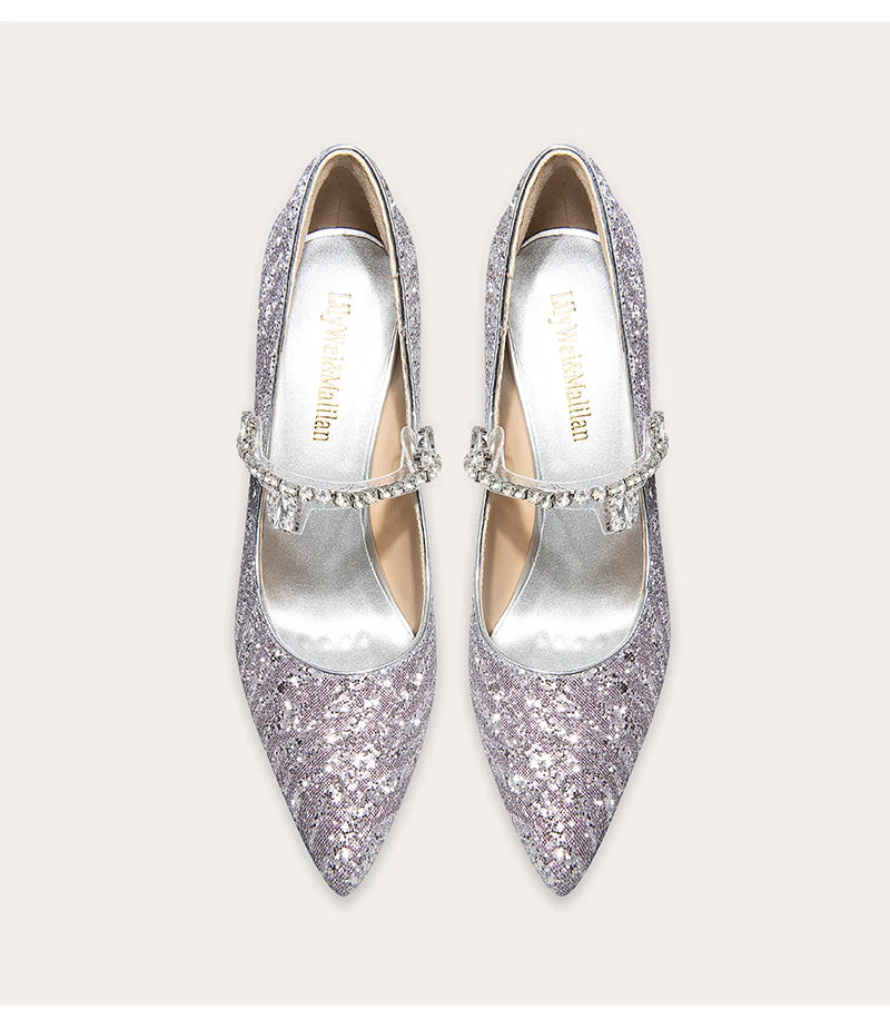 Pair of glittery silver high heels with embellishments on a light background
